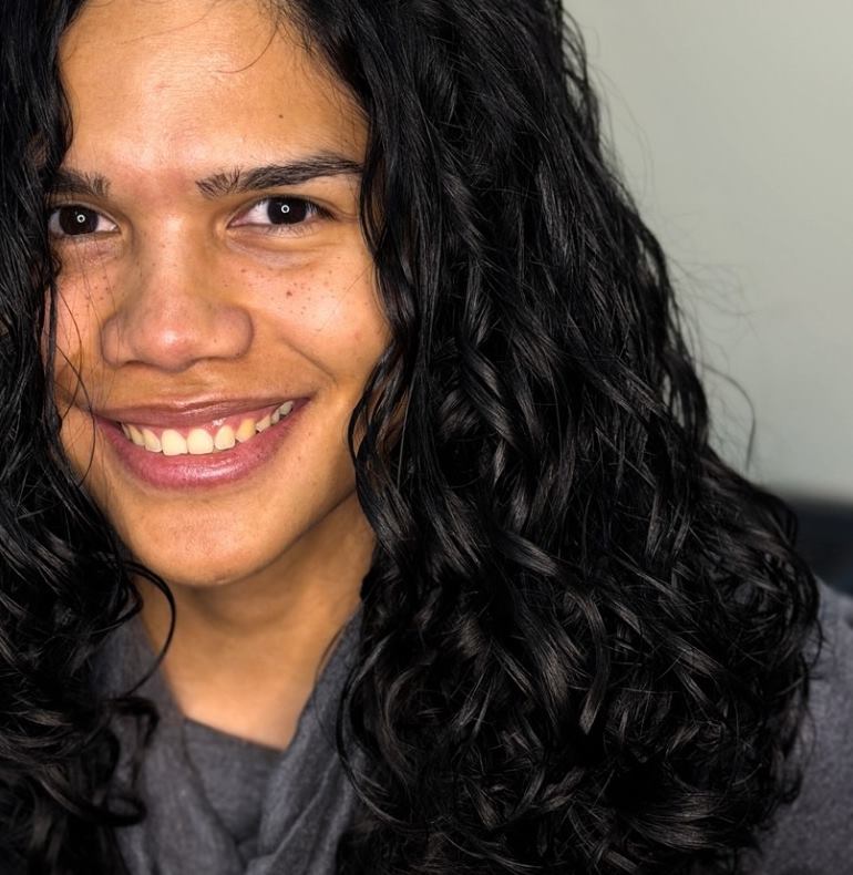Clienta sonriente con rizos negros largos, definidos y con movimiento