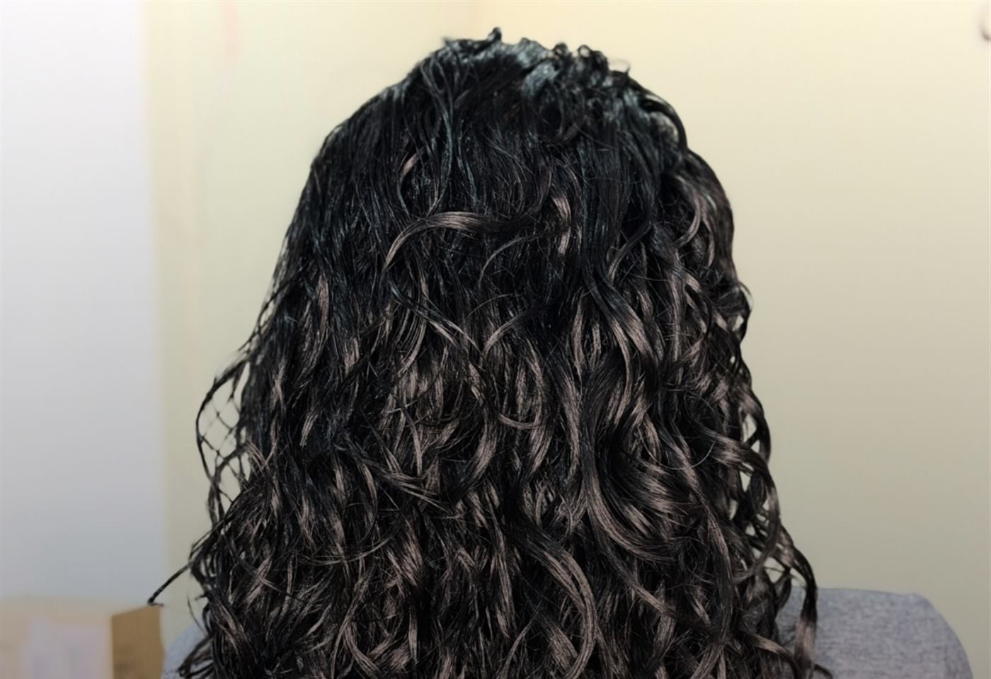 Espalda de una clienta con rizos negros largos recién definidos